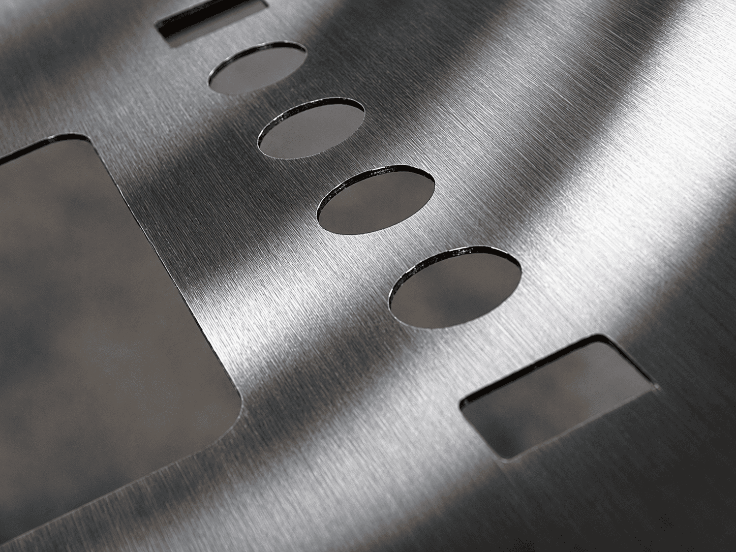 Piece of metal with CNC-machined cutouts.