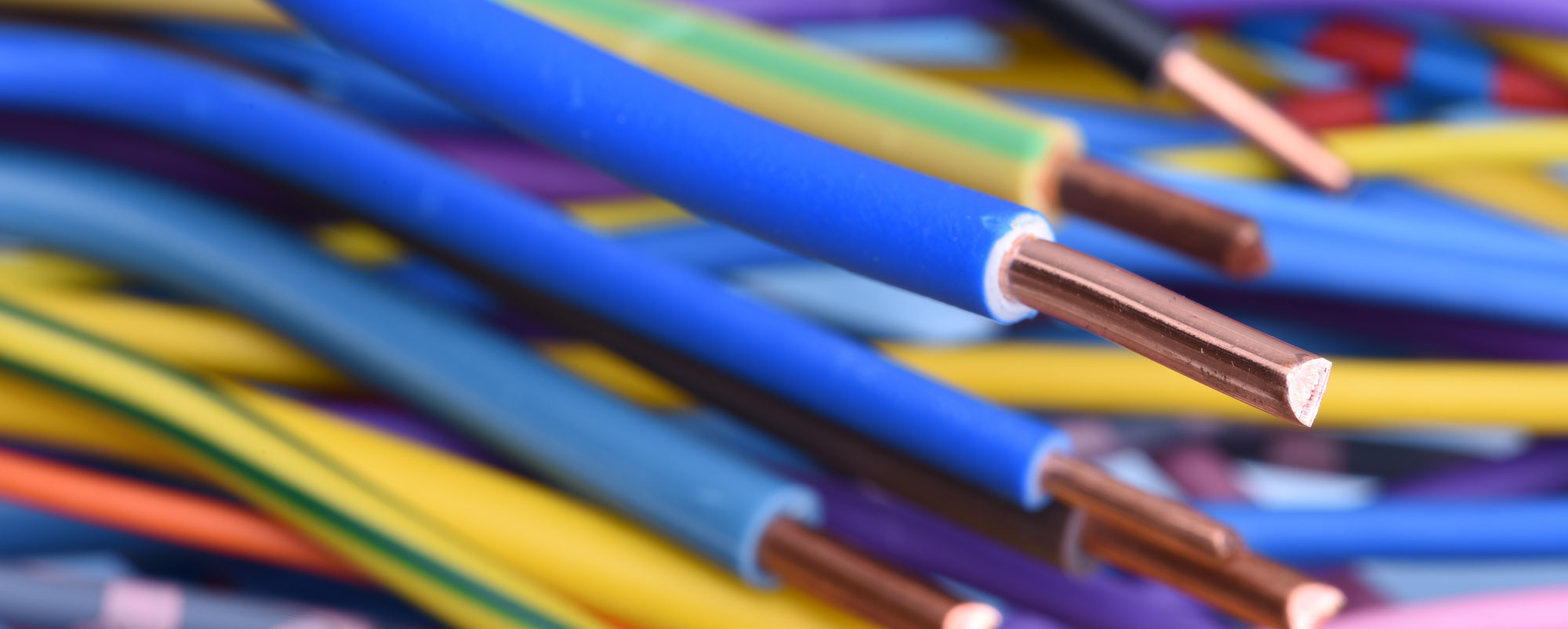 Close up of blue building wire with colorful blurred wires in the background